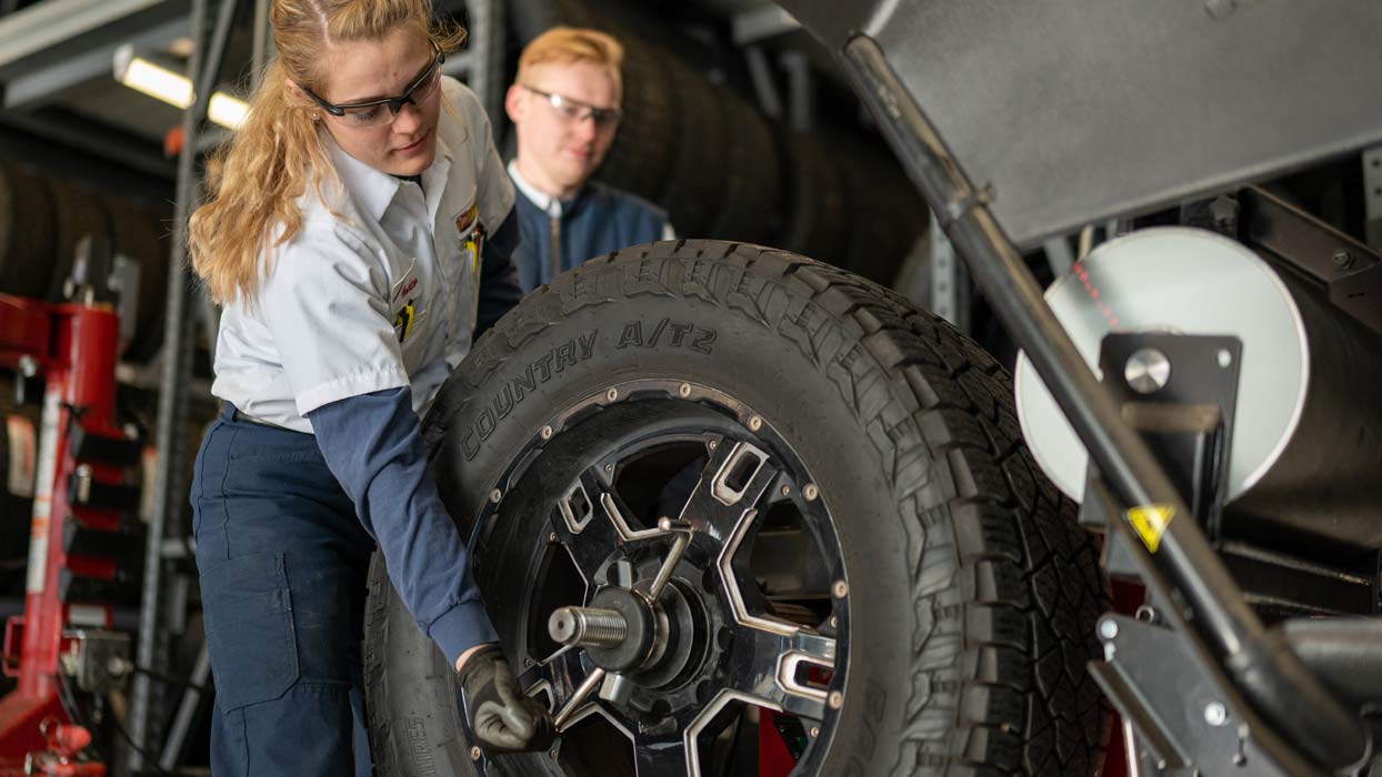 Female employee with a mounted tire on a wheel balancer