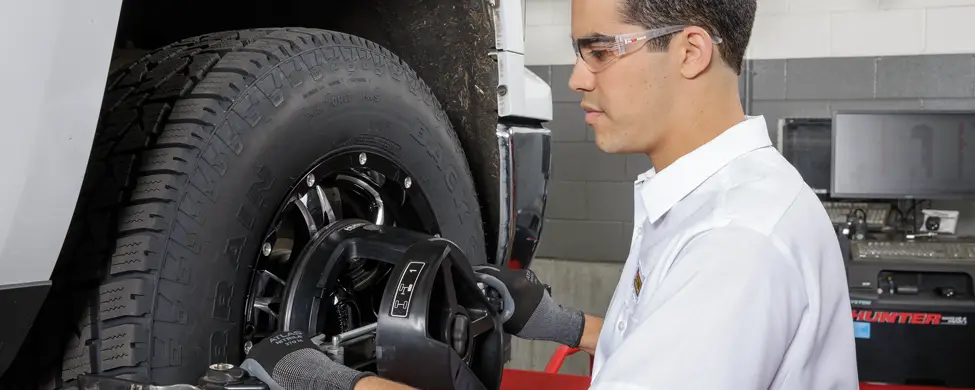 Les Schwab employee adjusting alignment on a pickup