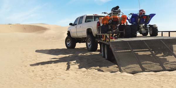 Truck with loaded trailer on sand dunes.