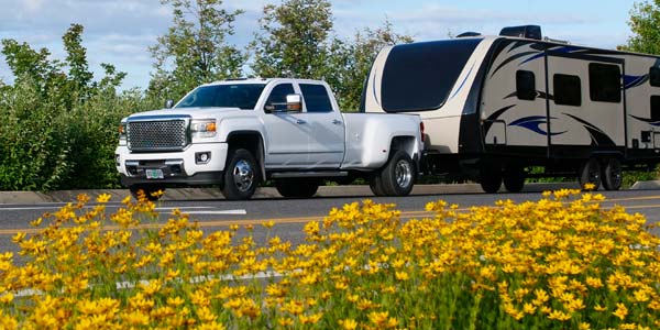 White truck pulling a long travel trailer.