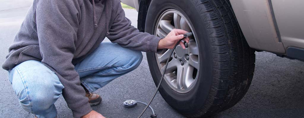 Man filling his car tire with air.