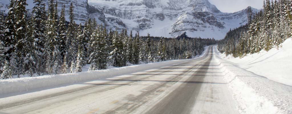 Icy mountain road with steep mountains in the distance.