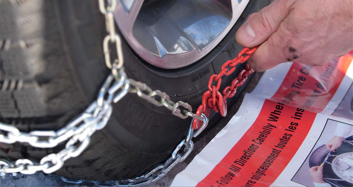 Pulling a long red chain through the chain guide on tire chains.