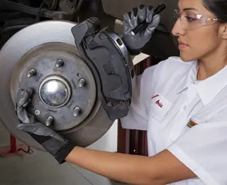 A Les Schwab technician completing a brake check on a brake assembly.