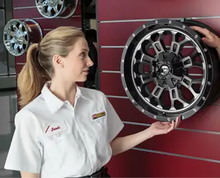 A Les Schwab saleswoman shows custom wheels and rims to a customer.