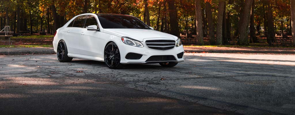 White sedan sitting in a parking lot during the fall.