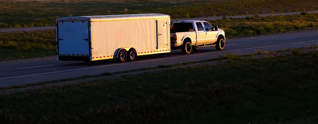 Pickup pulling long utility trailer at dusk