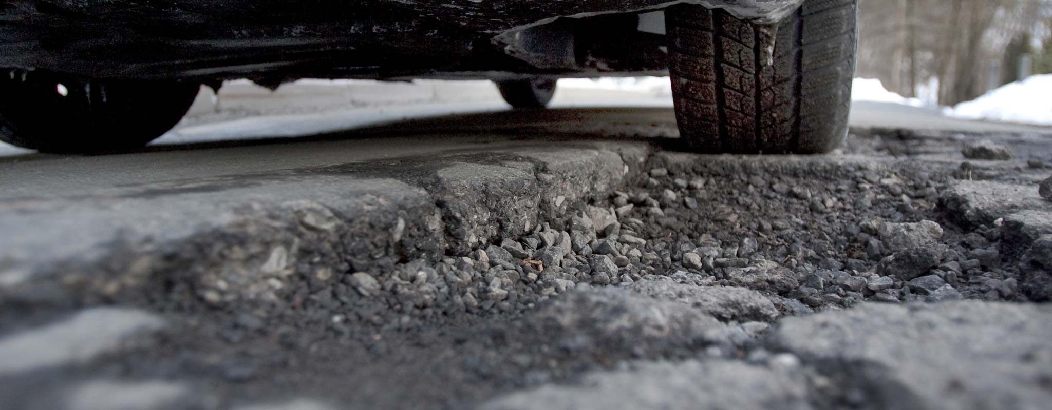 A car tire about to go through a pothole.