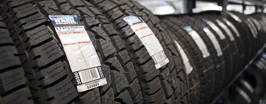 A row of new tires sitting on metal shelving.