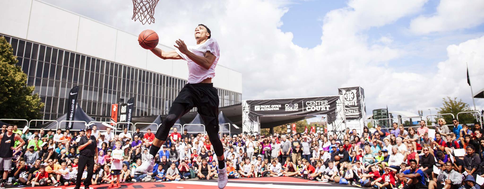 Fans watch a player attempting to slam dunk a basketball.