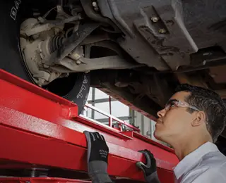 Les Schwab technician looking behind a wheel assembly.