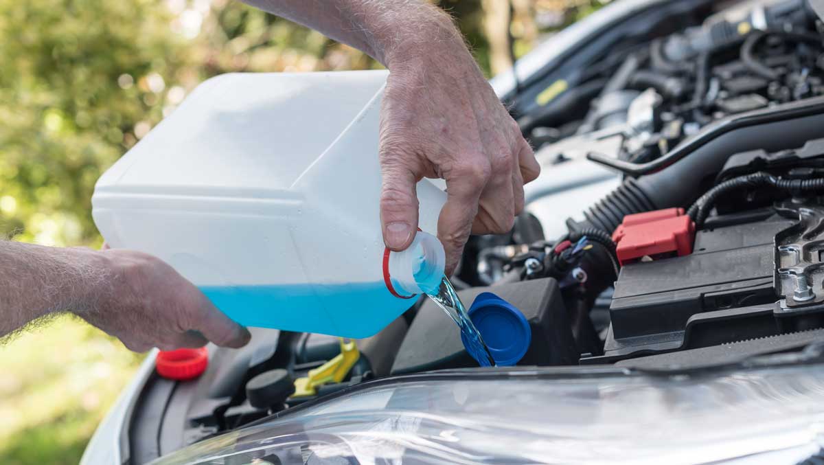 Man filling washer fluid tank on car