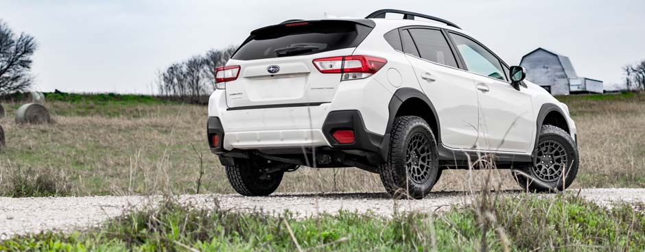 White CUV with overlanding kit installed.