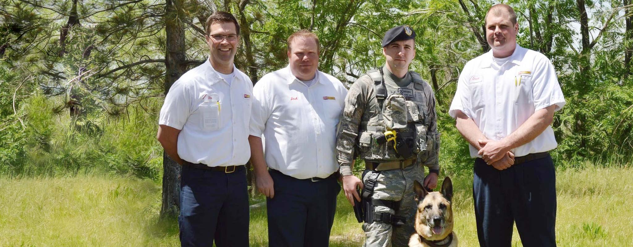 Three Les Schwab managers pose with a military dog and its owner, Frank Wehner.