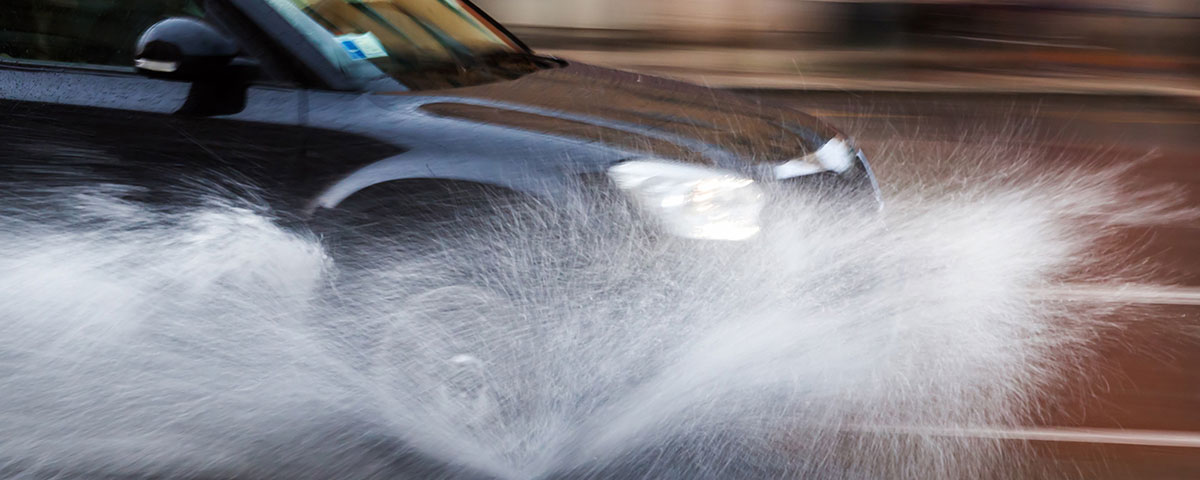 Car driving through puddle in rain