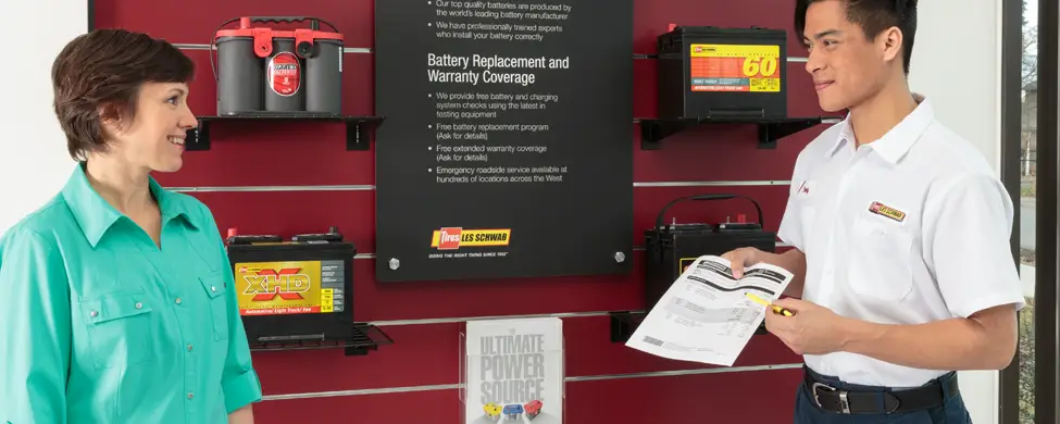 Les Schwab employee showing battery options to a customer