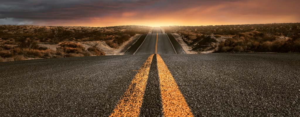 A sunset at the end of a long straight road.
