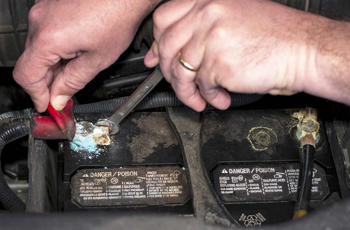 Tech examining corroded battery pole