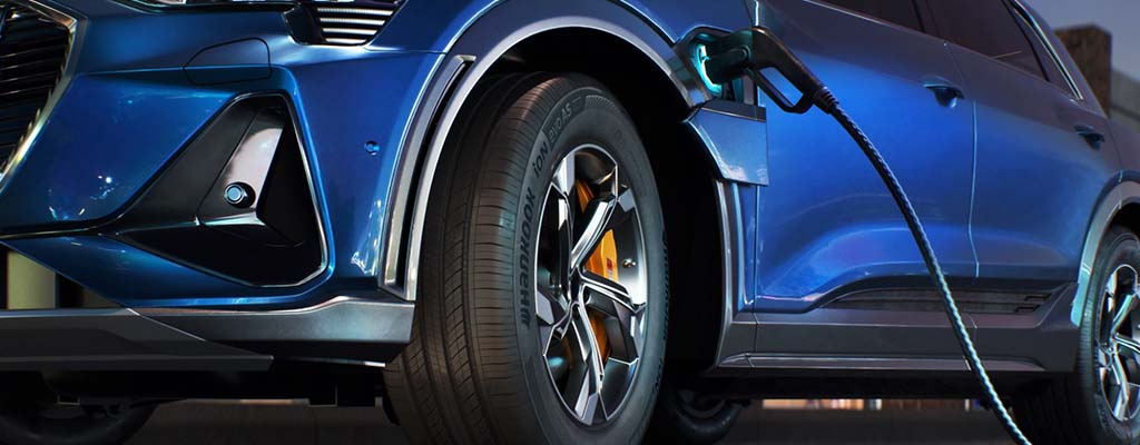 A blue electric vehicle charging at night.