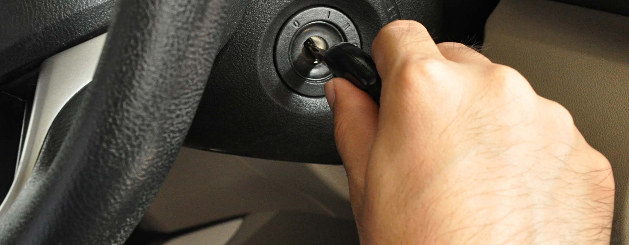 A hand putting a key in a car ignition.