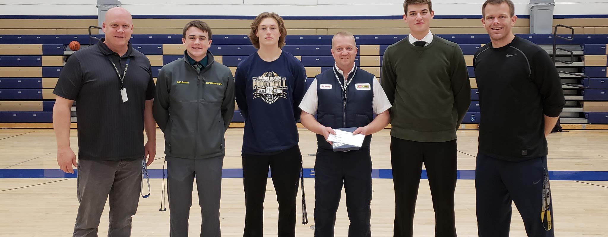 A Les Schwab manager poses in a gym with an Oregon sports team.