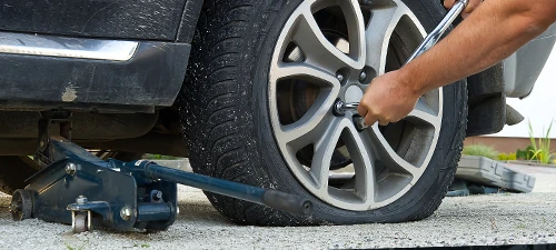 Car with a deflated tire on a car jack