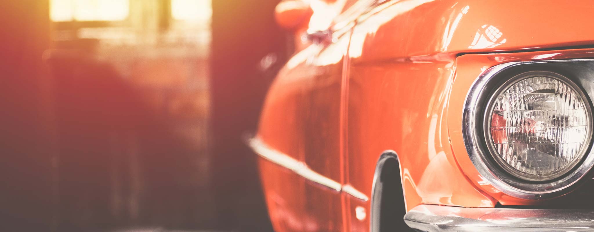 A red classic car in a garage.
