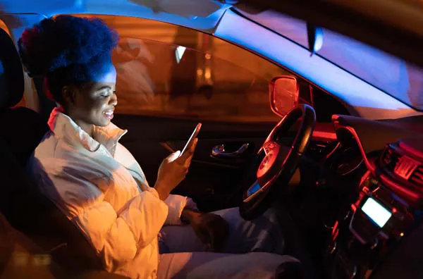 Woman looking at her phone while sitting in a car